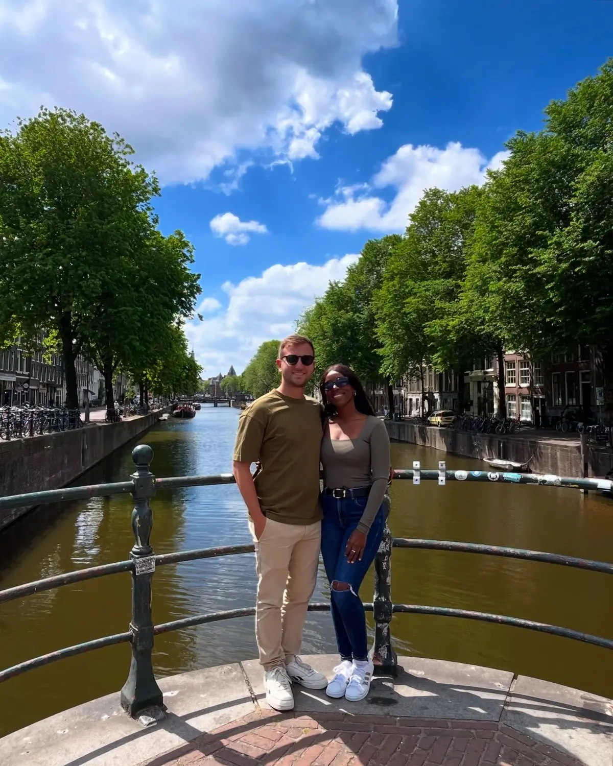 Us on a bridge over a tree-lined canal in Amsterdam under a bright blue sky