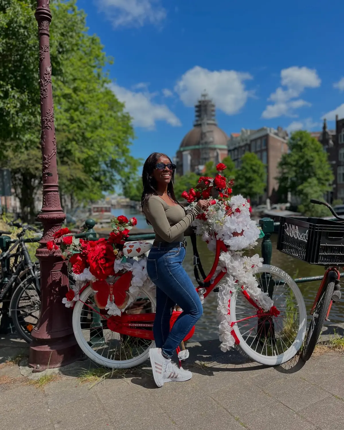 Melody beside the famous flower-covered red 'Flower Bike Man' bicycle on an Amsterdam bridge