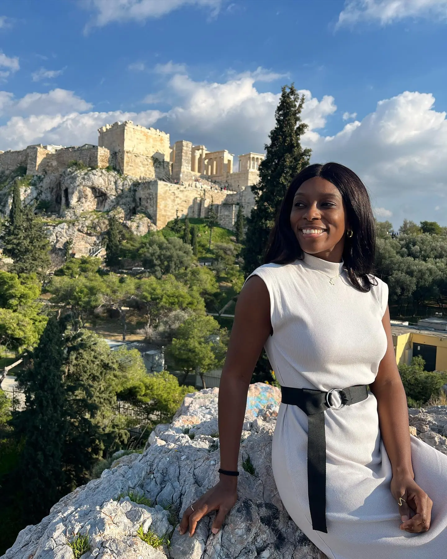 Melody seated on the rocks with the Acropolis rising behind