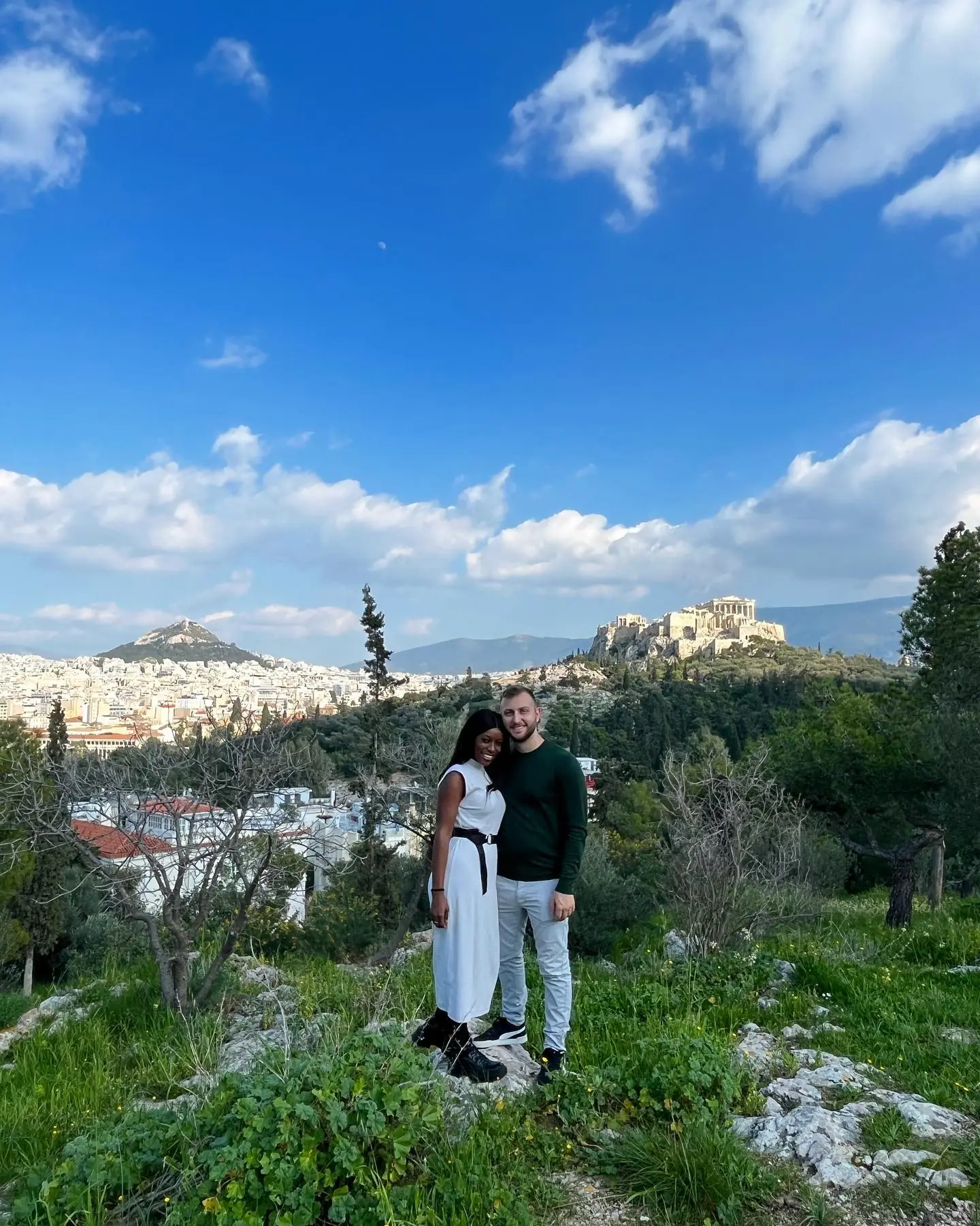 Us on a green hill with the Acropolis and Lycabettus in the distance