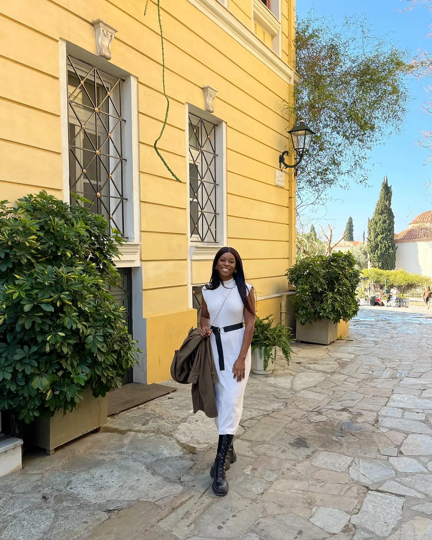 Melody on a cobbled Plaka lane beside a yellow neoclassical house