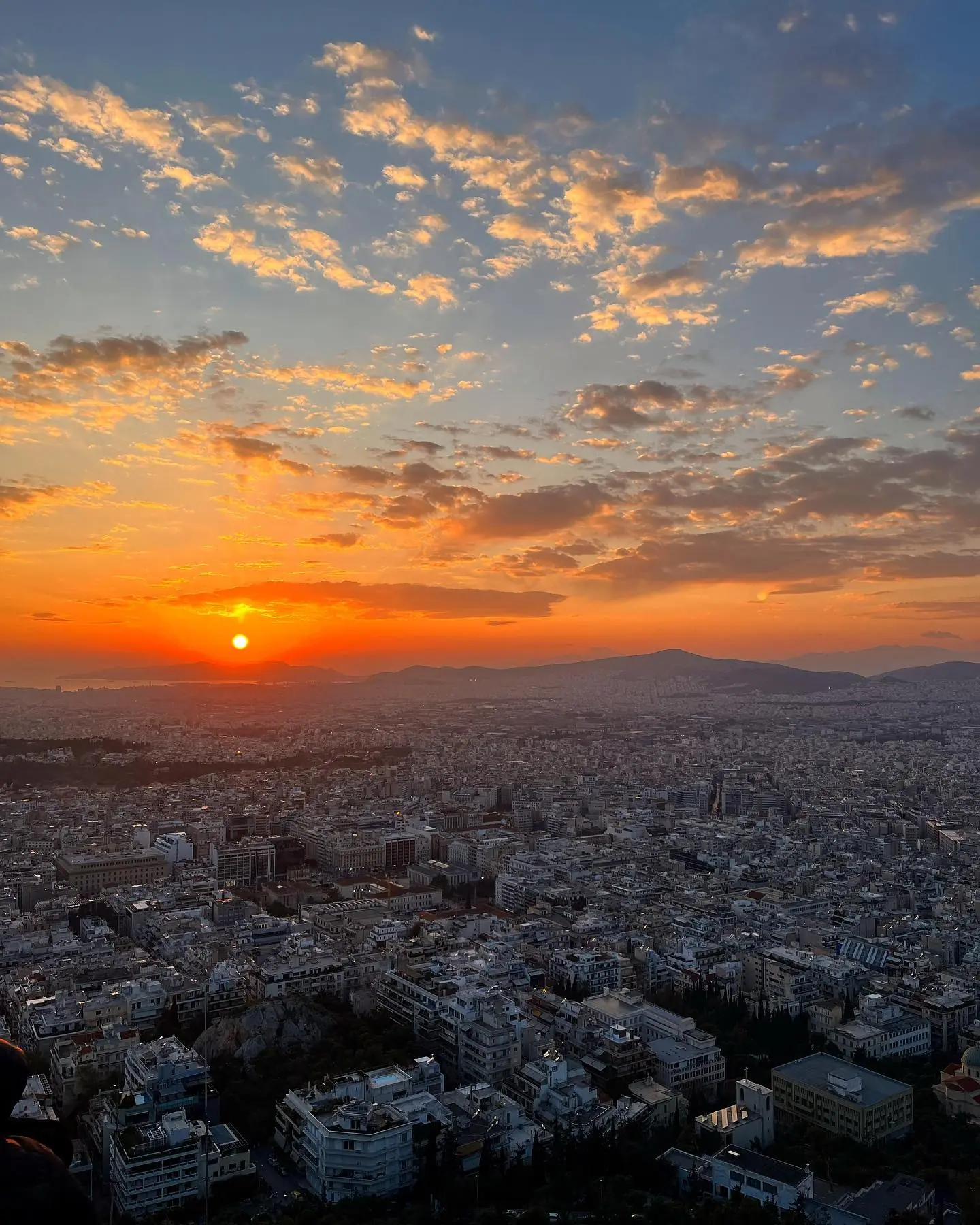 A fiery sunset over the sprawl of Athens seen from a hilltop