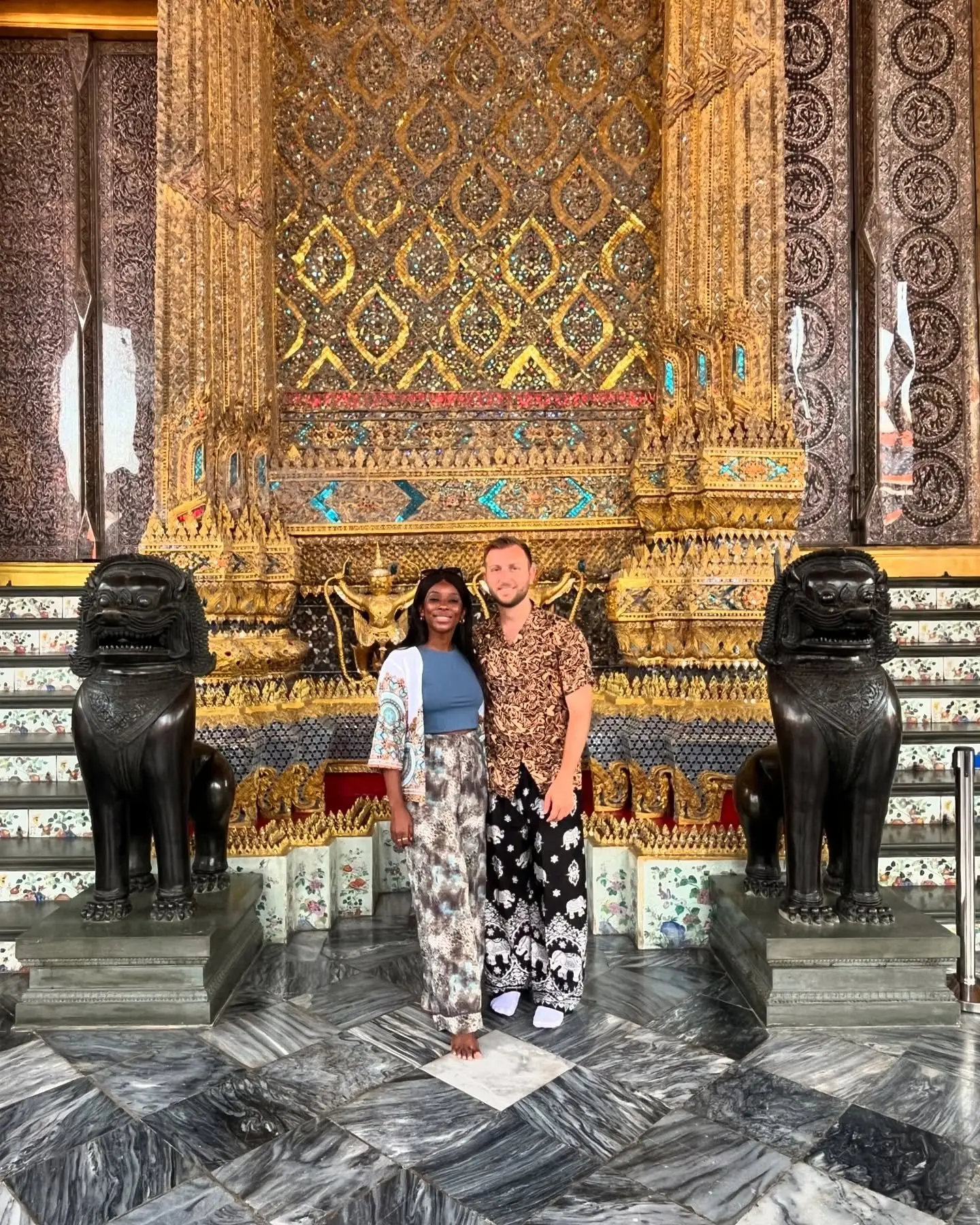 Us inside a gilded hall of the Grand Palace flanked by lion statues