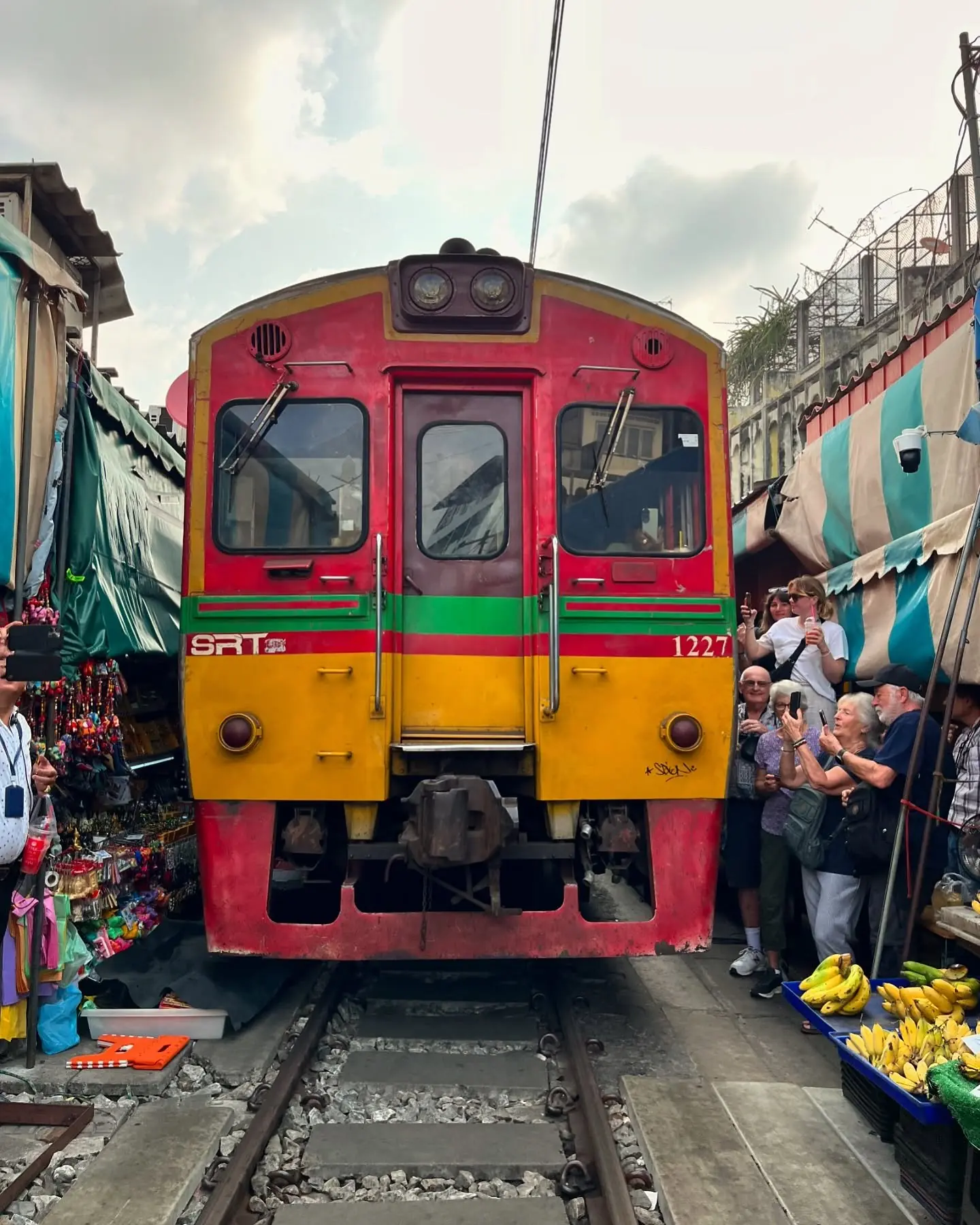 A train pushing through the Maeklong Railway Market