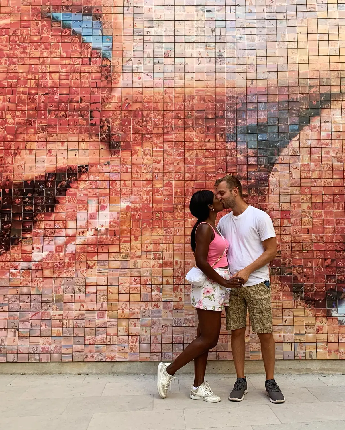 Us kissing in front of the photomosaic 'The World Begins with Every Kiss' mural in Barcelona