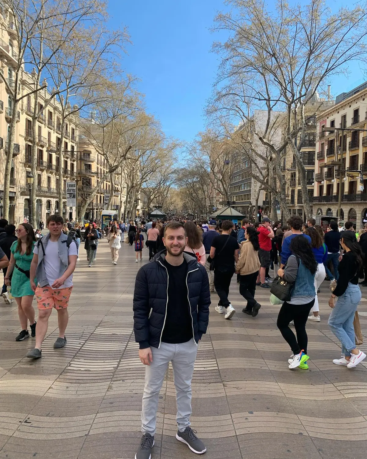 Andrew standing on the wide, tree-lined La Rambla promenade in Barcelona
