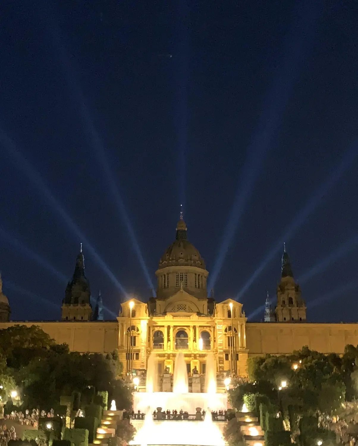 The Magic Fountain of Montjuïc lit up at night in front of the illuminated MNAC palace