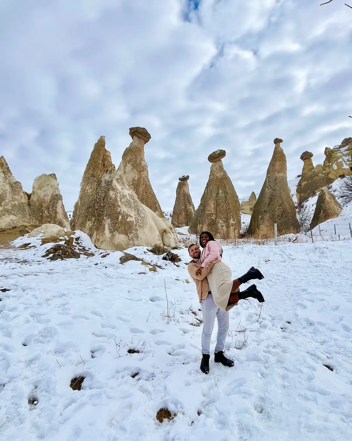 Andrew lifting Melody, both laughing, among tall fairy chimneys
