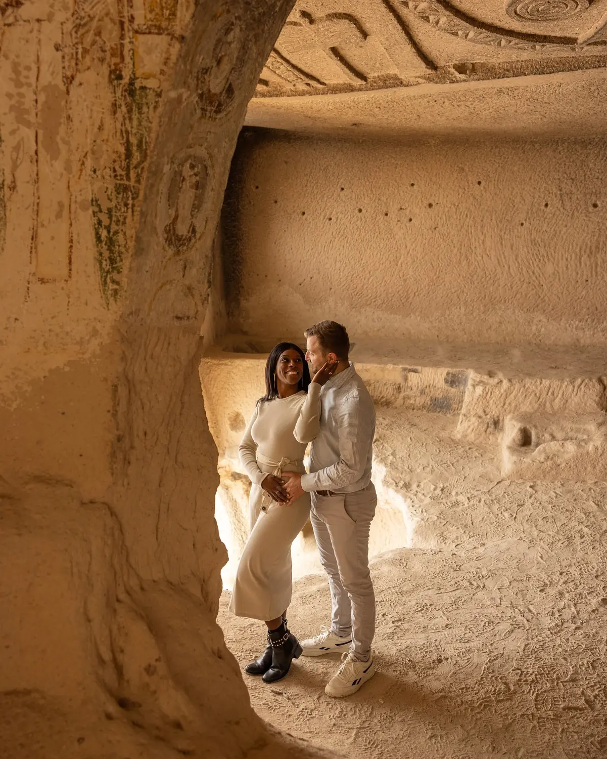 Us embracing in a carved cave with painted ceiling