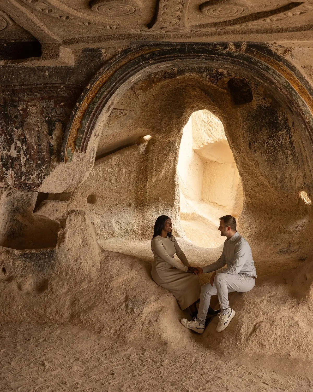 Us sitting holding hands in a frescoed cave church