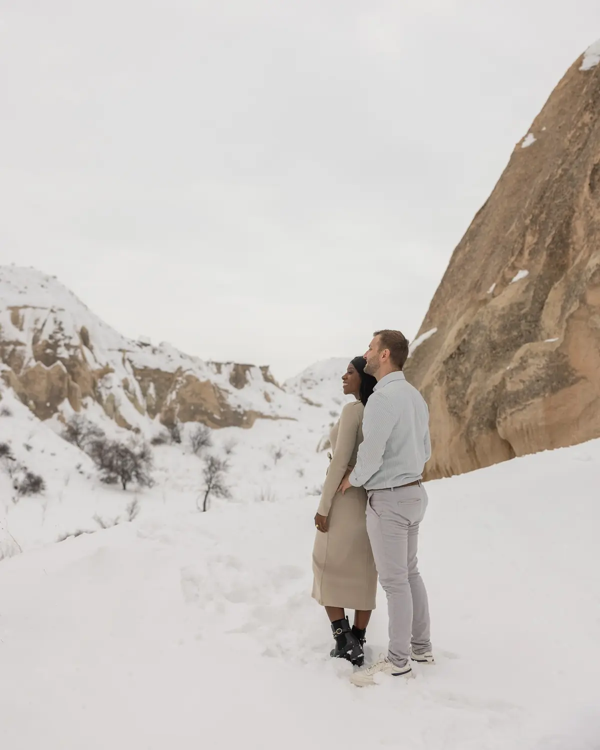 Us standing beside a huge snow-dusted rock, taking in the valley view