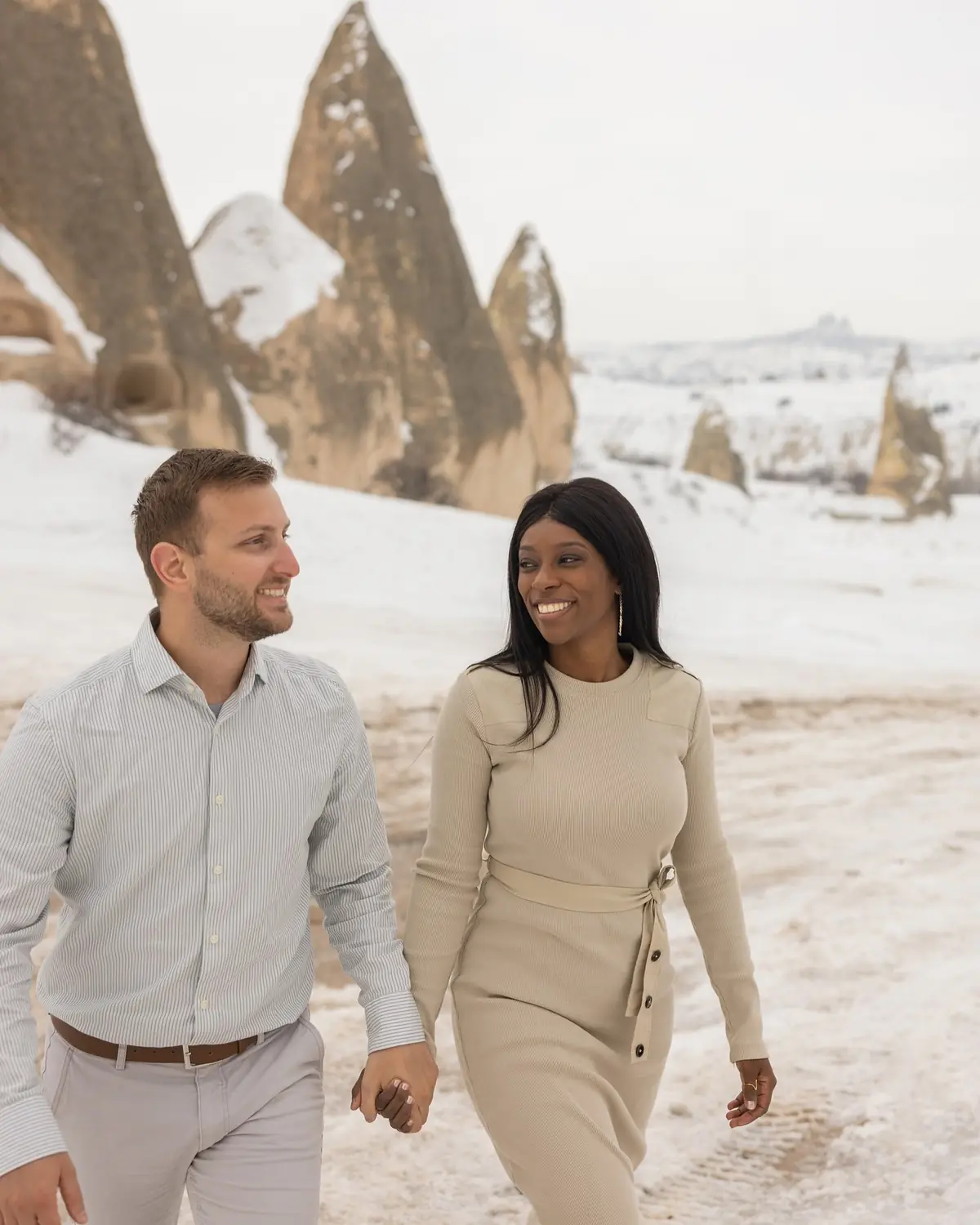Us walking hand in hand and smiling at each other in the snow