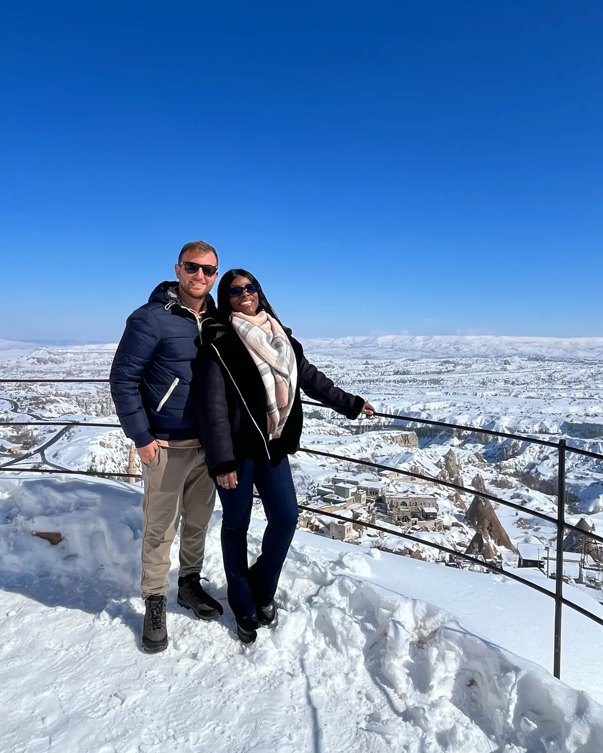 Us at a railed viewpoint over a vast snowy Cappadocia valley