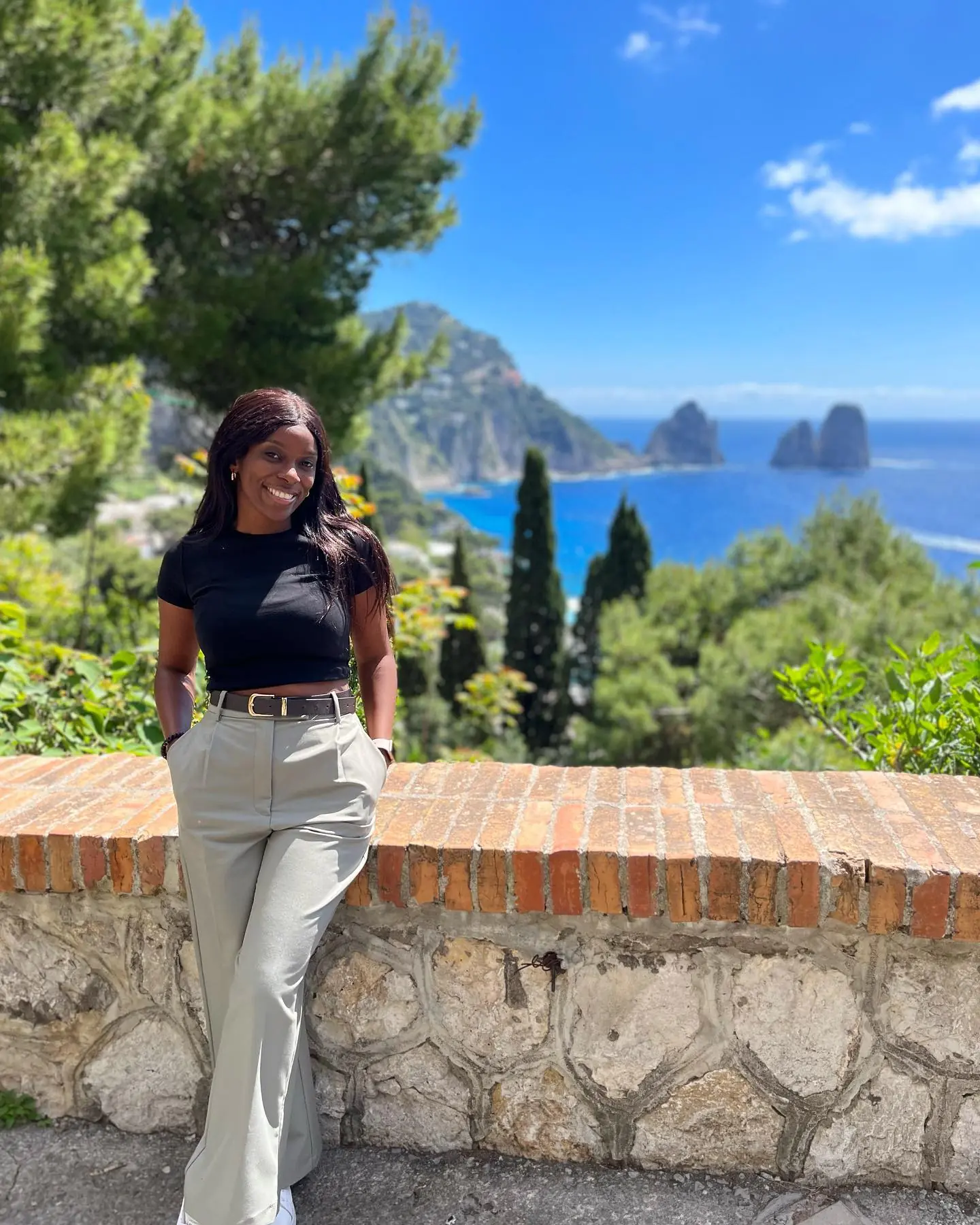 Posing at a brick wall with the Faraglioni sea stacks behind