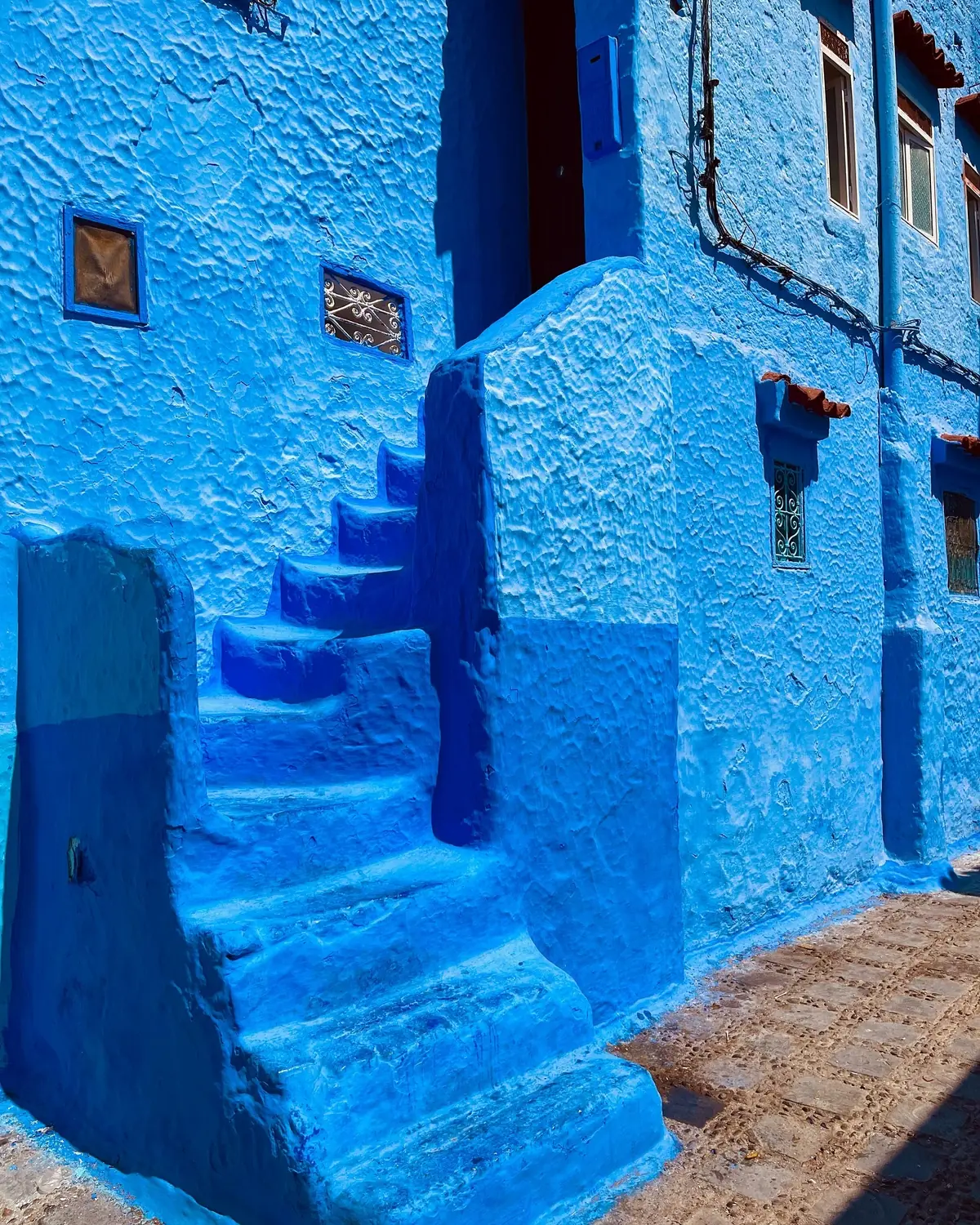 Blue-painted steps and walls with wrought-iron windows in the Chefchaouen medina