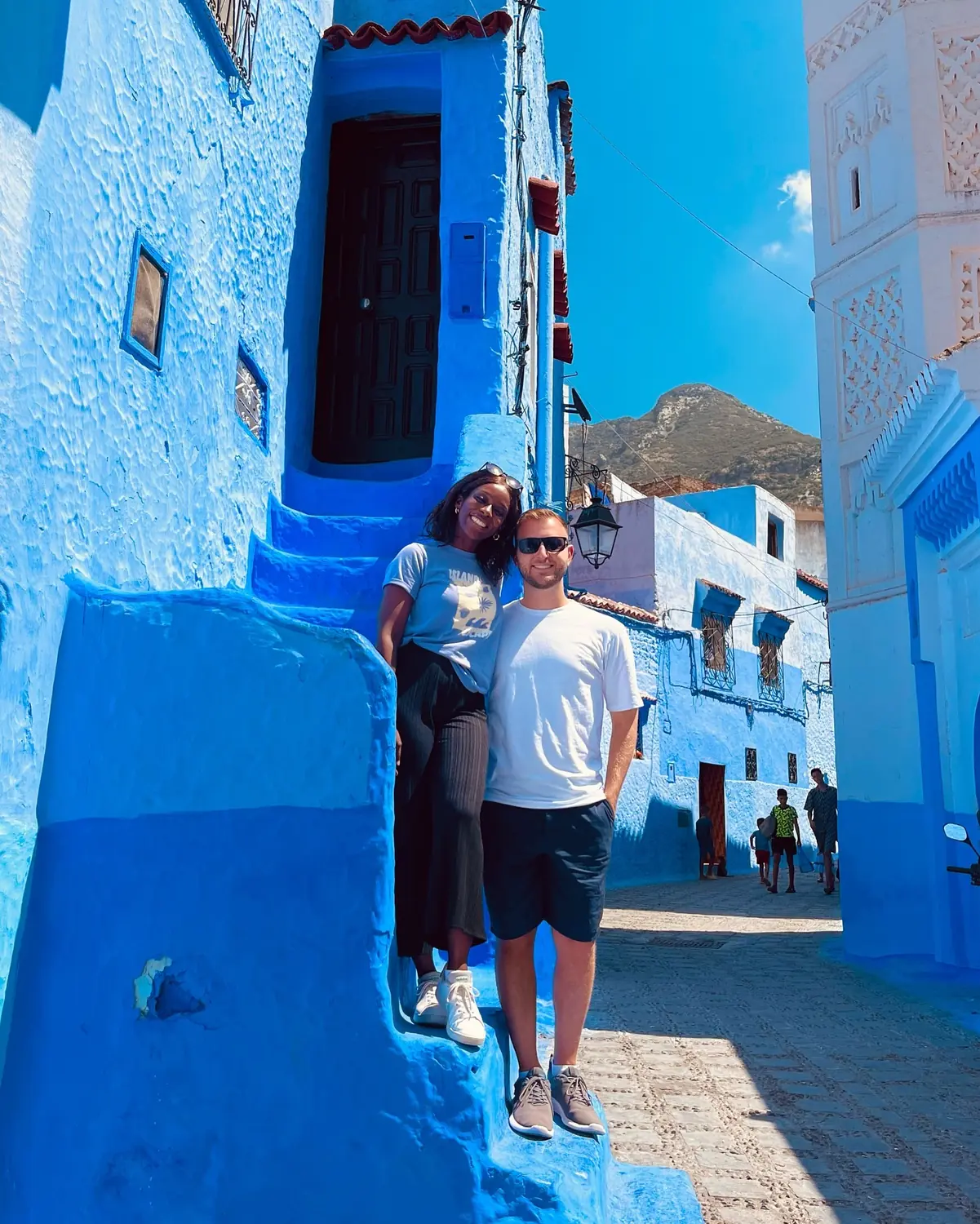 Us on blue steps with a minaret and the Rif mountains behind