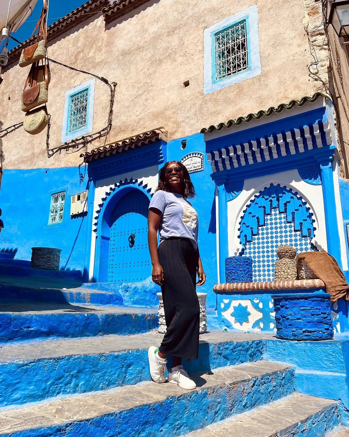 Melody by an ornate blue-tiled fountain and keyhole doorway in Chefchaouen