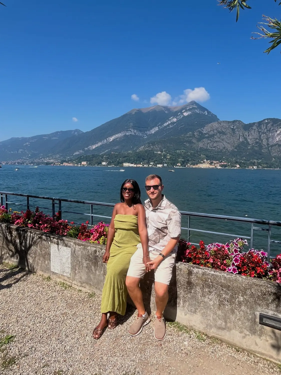 Us on a flower-lined lakeside wall