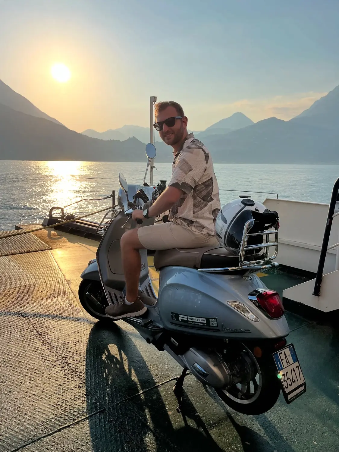 Andrew on the Vespa aboard the lake car ferry at sunset