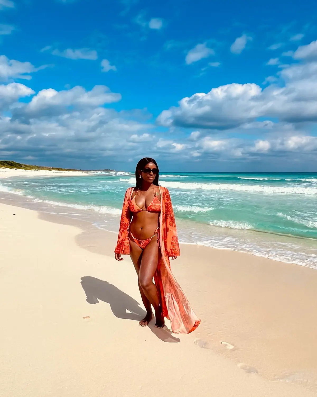 Melody walking a long empty Cozumel beach in an orange cover-up