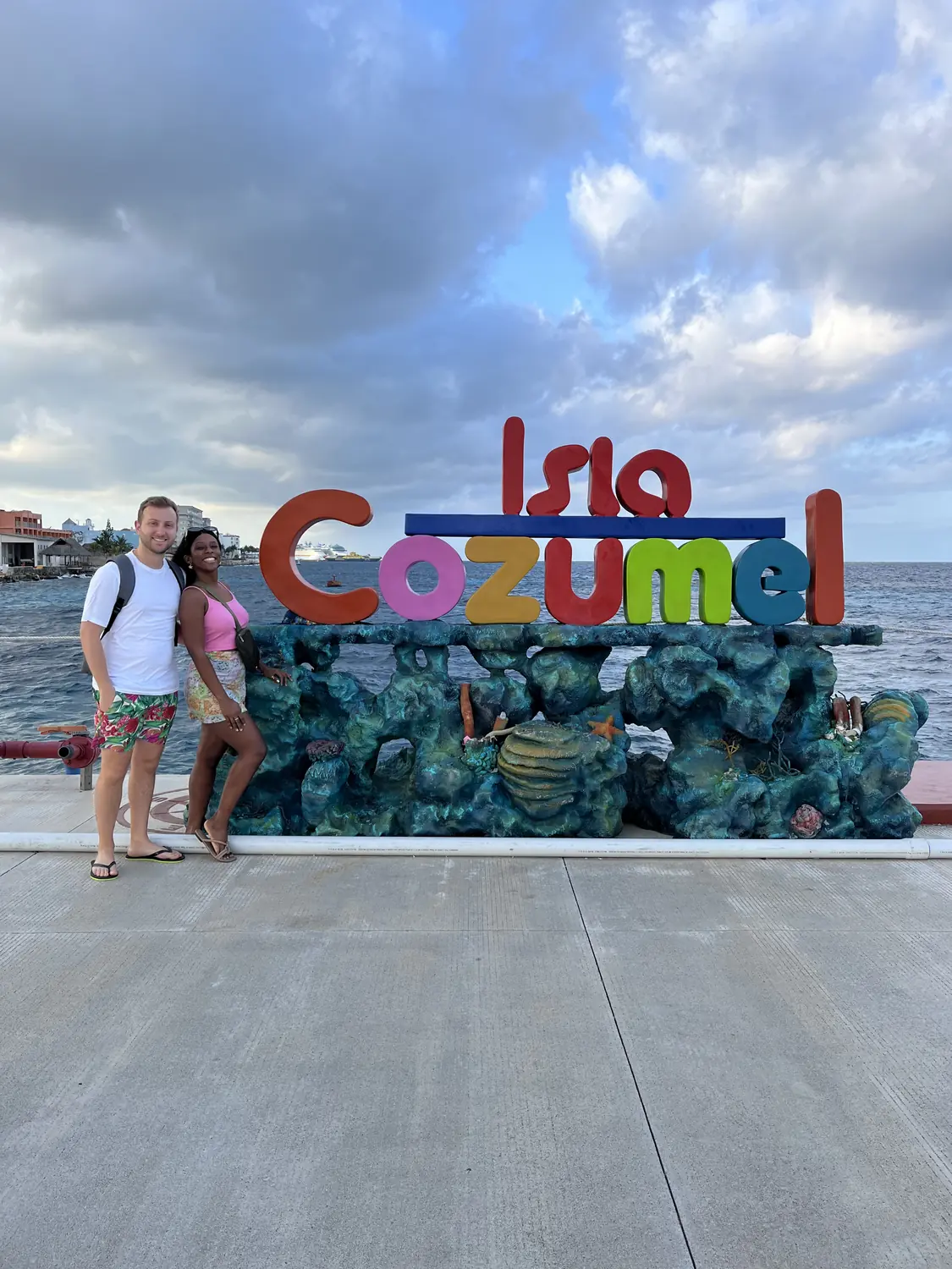 Us in front of the colourful Isla Cozumel sign on the waterfront
