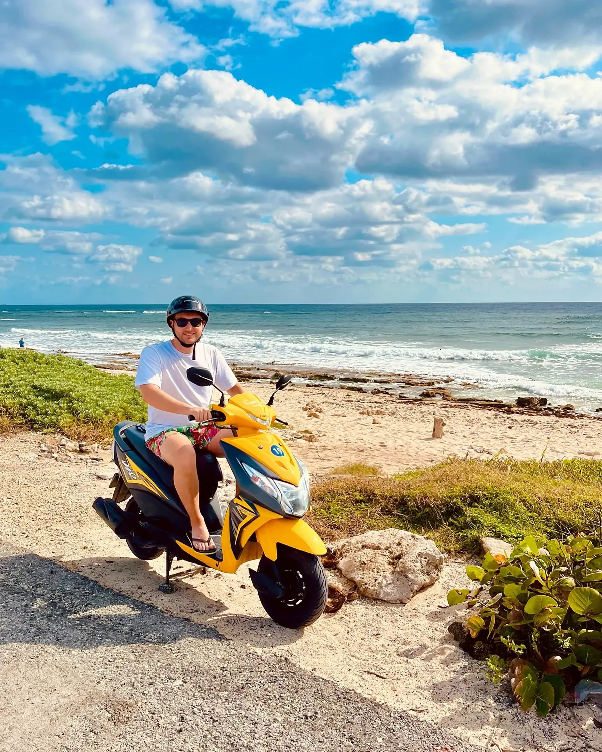 Andrew on a yellow rental scooter by the rocky Cozumel coast