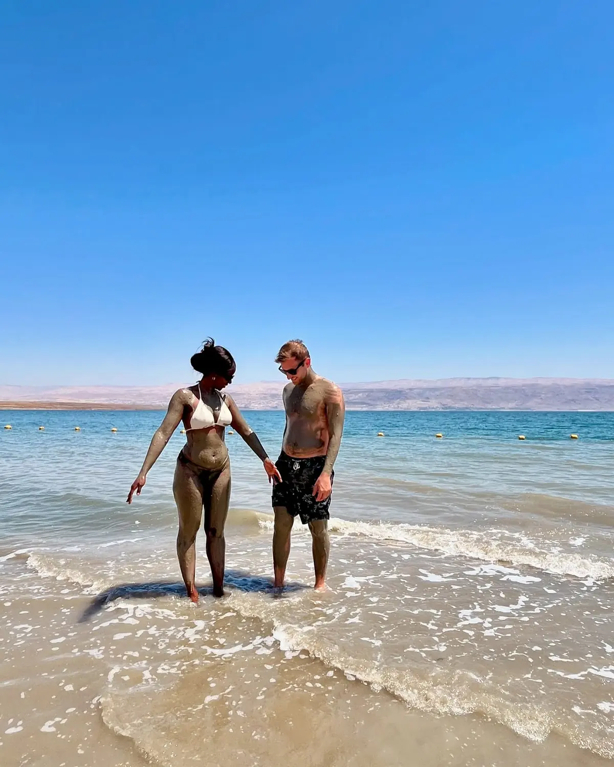 Us covered in mineral mud at the edge of the Dead Sea