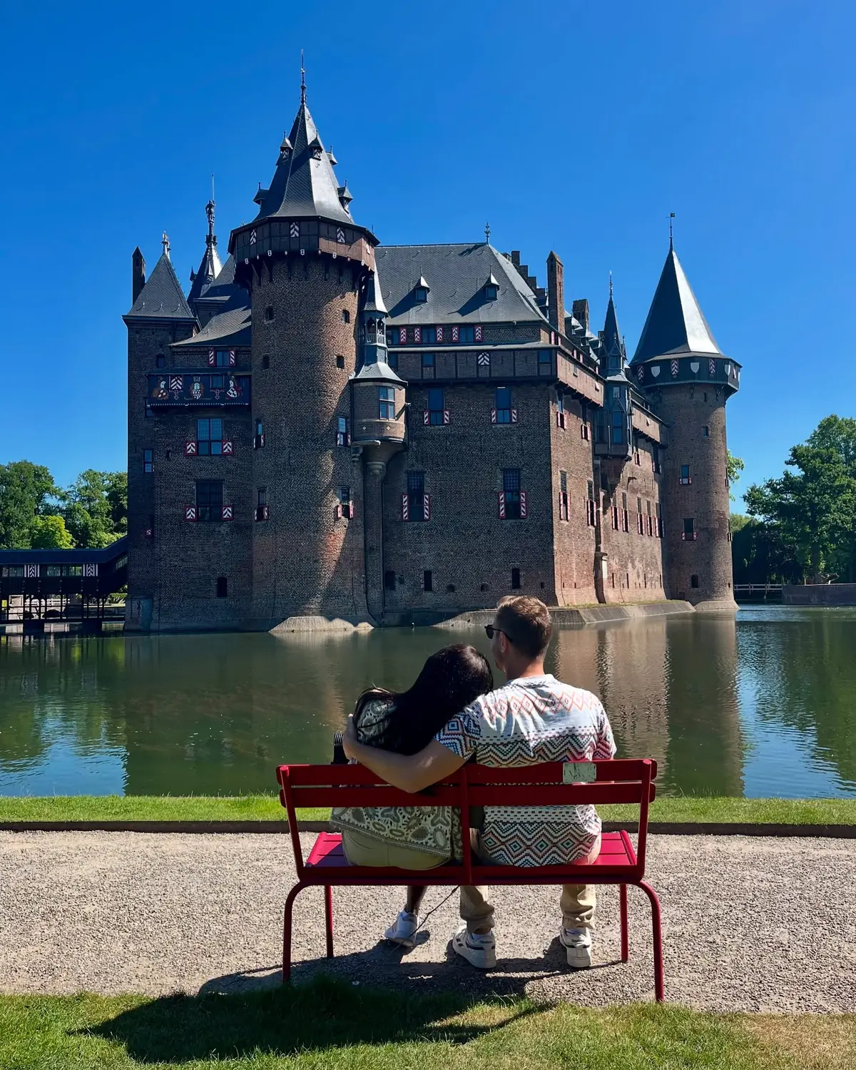 Us on a red bench looking across the moat at Kasteel de Haar