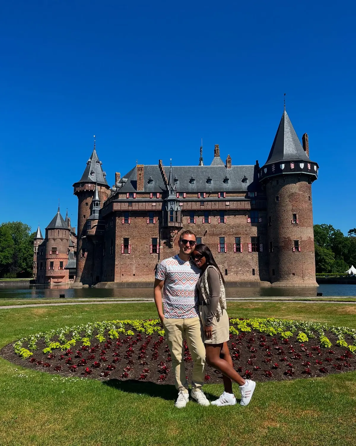 Us in front of the fairy-tale turrets of Kasteel de Haar with a formal flower bed