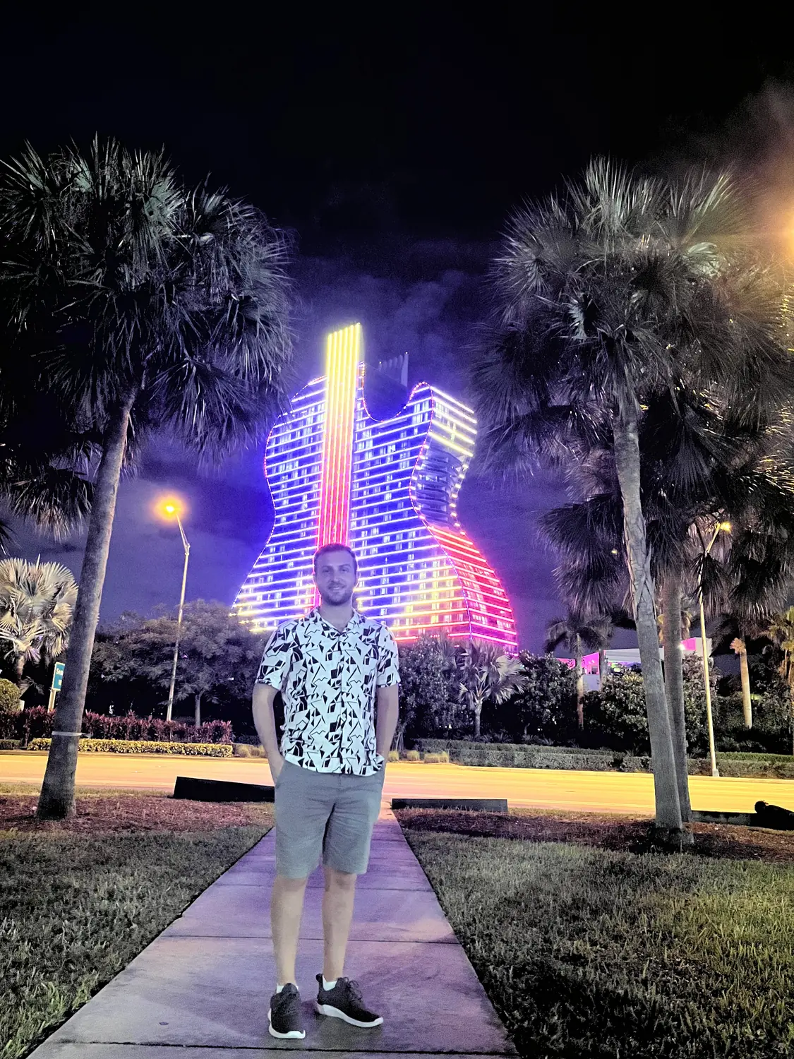 Andrew in front of the illuminated Guitar Hotel at the Seminole Hard Rock at night