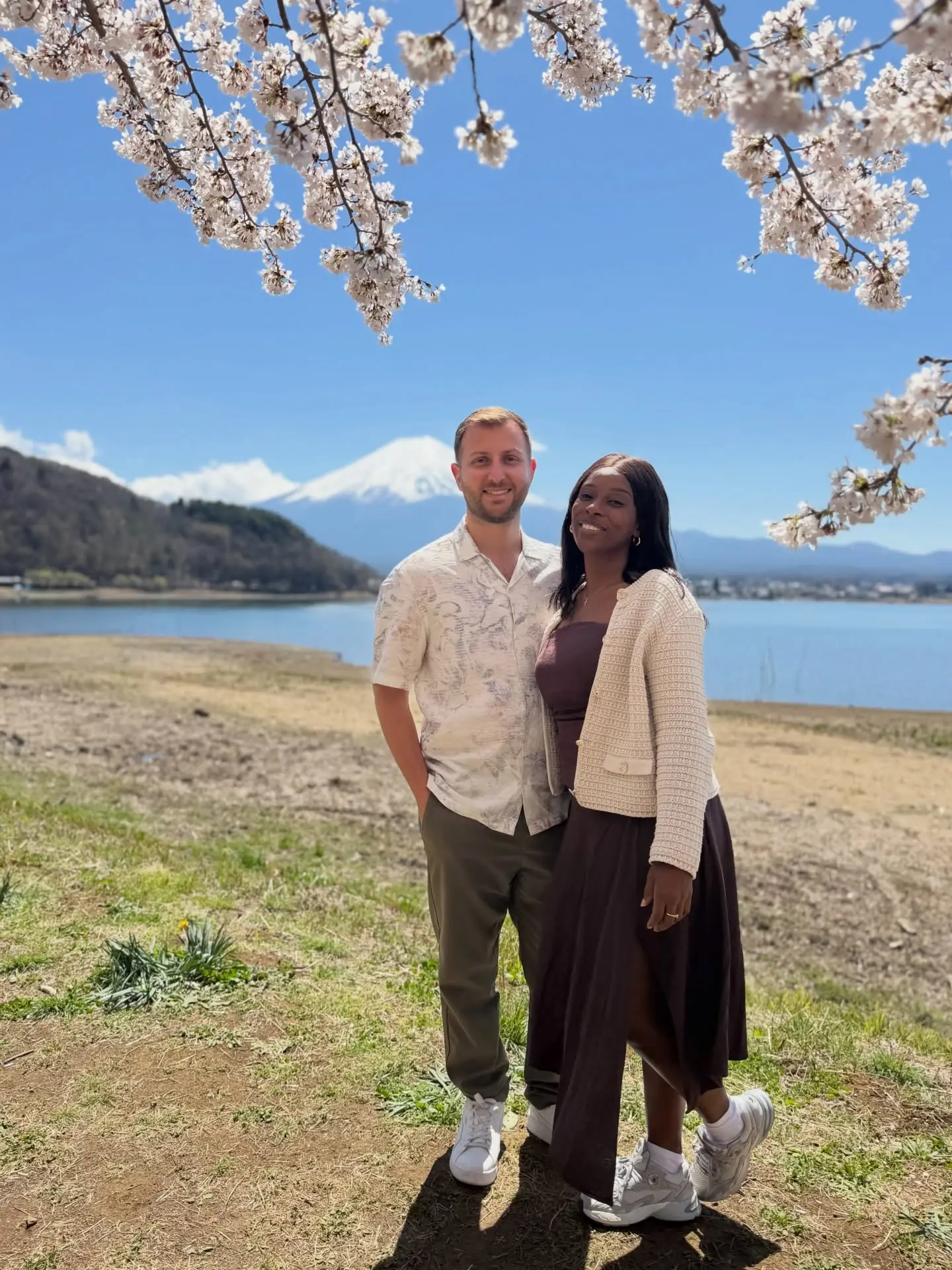 Us with snow-capped Mount Fuji and cherry blossoms across the lake