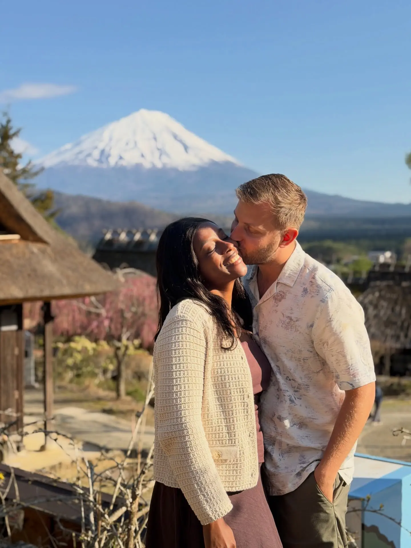 A kiss with Mount Fuji and a thatched-roof village behind