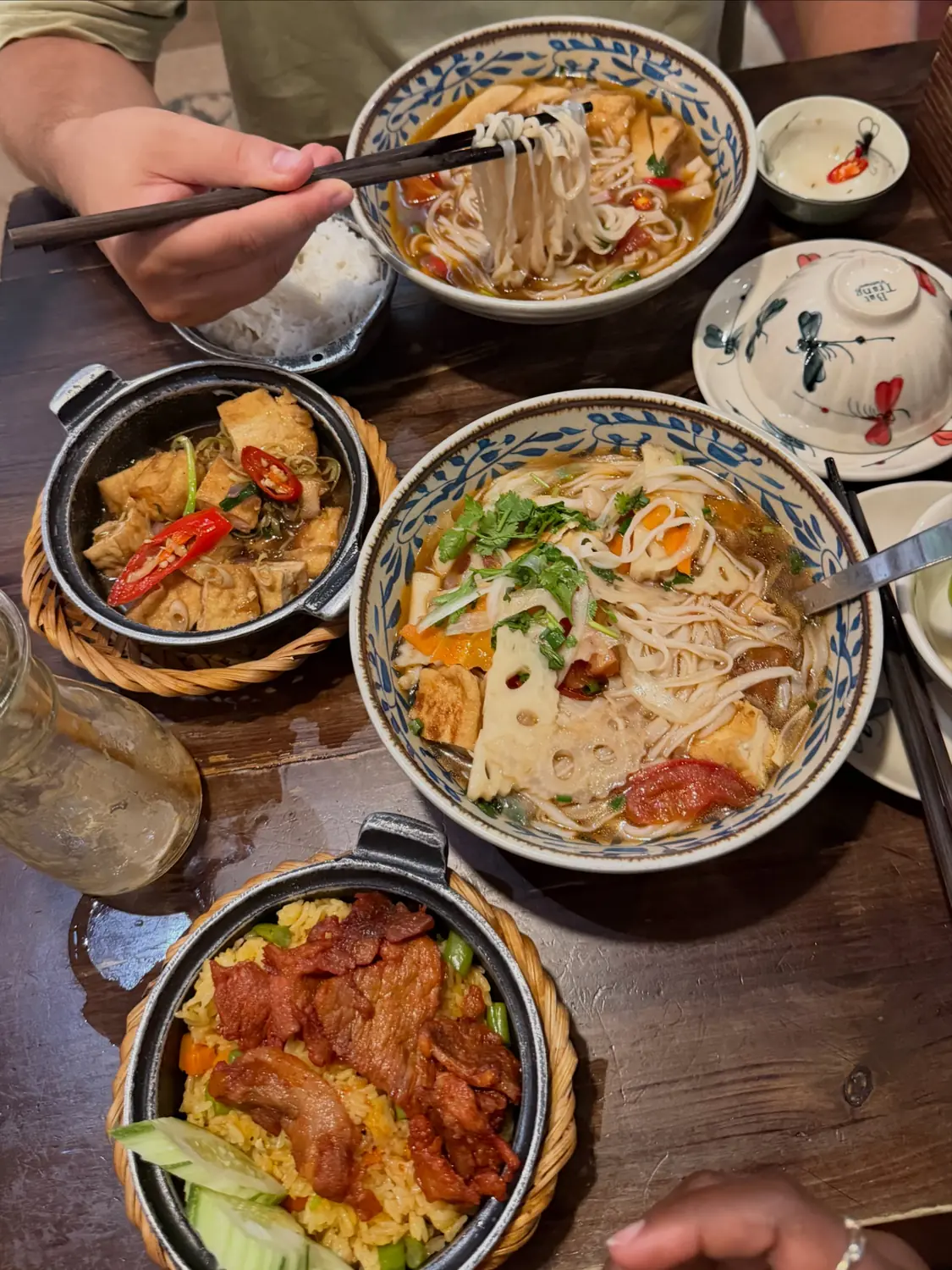 A spread of Vietnamese noodle soups and clay-pot dishes on a wooden table