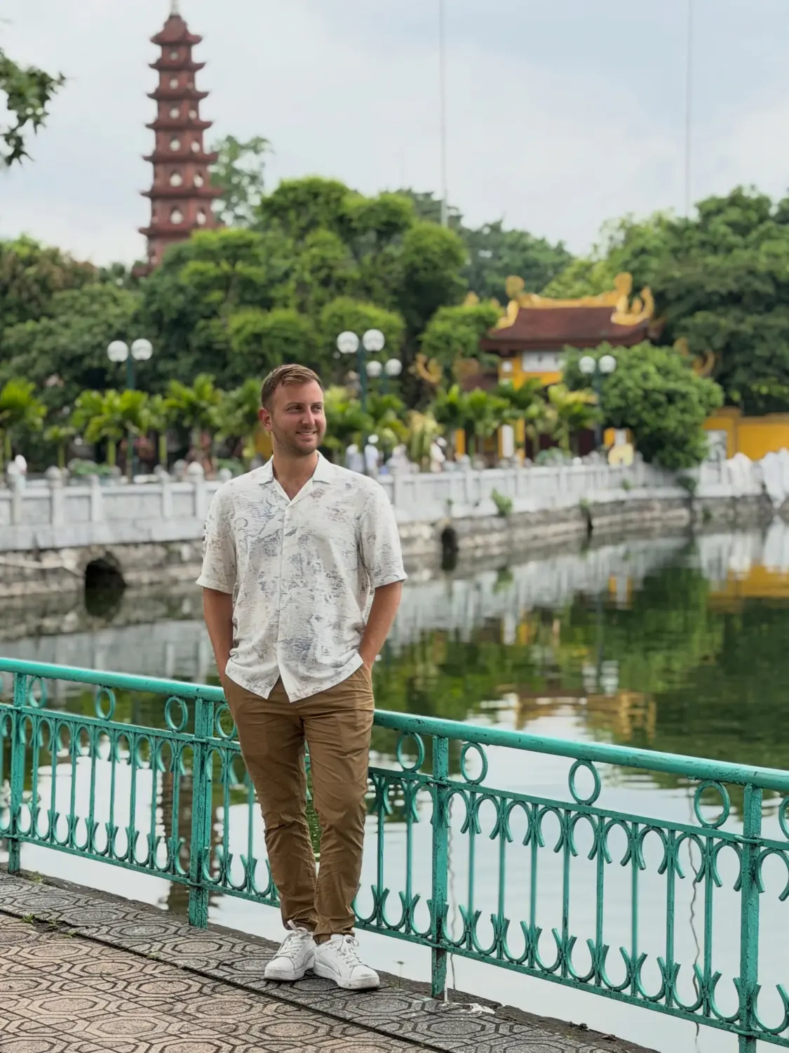 Andrew by West Lake with the red tiers of Tran Quoc Pagoda behind