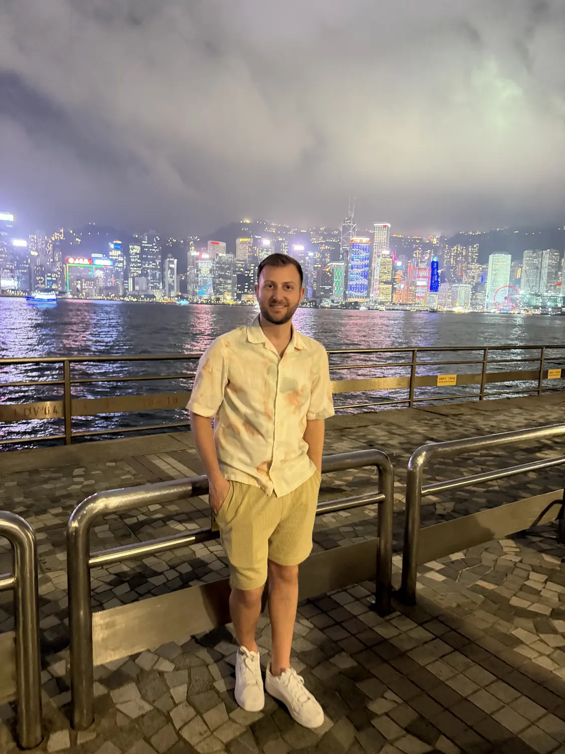 Andrew at the harbour promenade at night with dazzling skyline lights