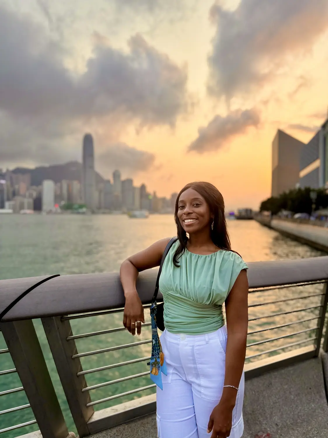 Melody on the Victoria Harbour promenade with the Hong Kong skyline behind at sunset