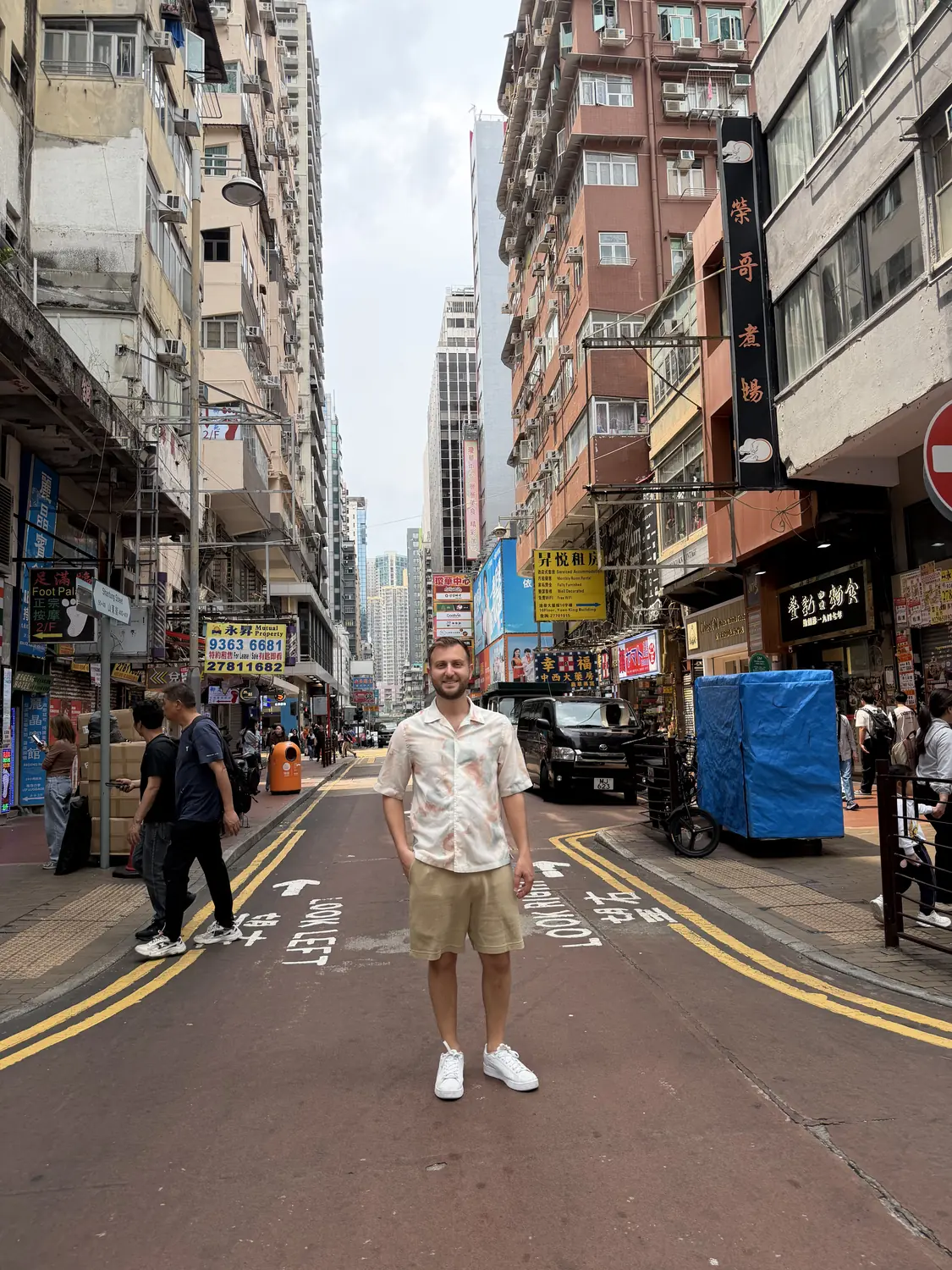 Andrew on a busy old Hong Kong street with tram wires overhead