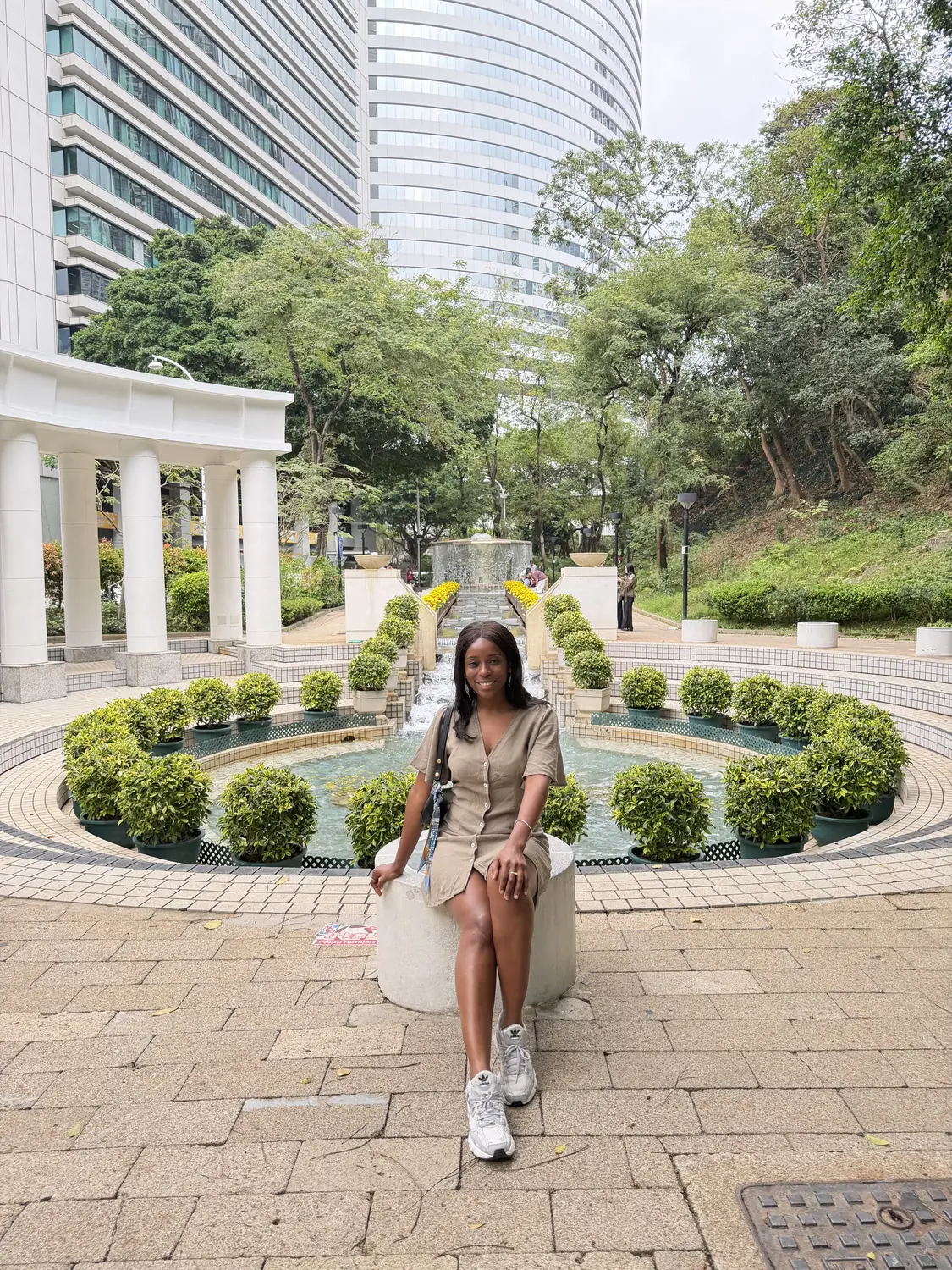 Melody in Hong Kong Park with a colonnade and skyscrapers behind