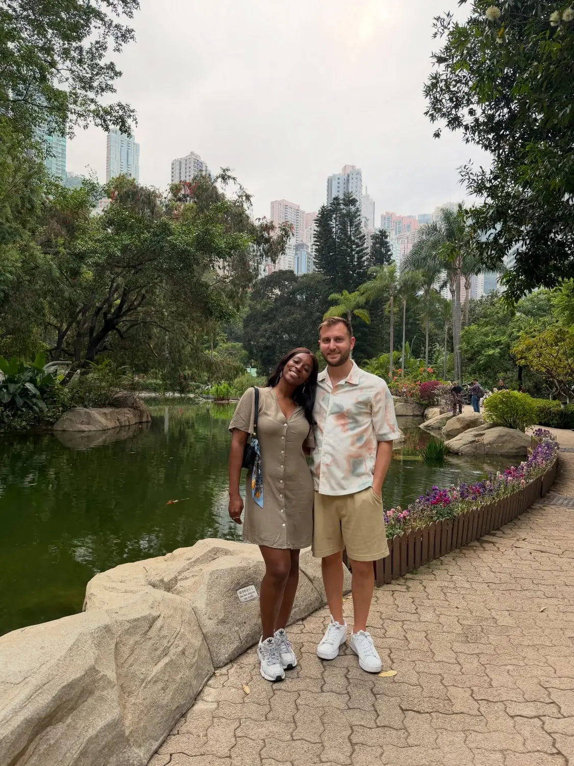 Us by a koi pond in Hong Kong Park with skyscrapers rising behind the trees