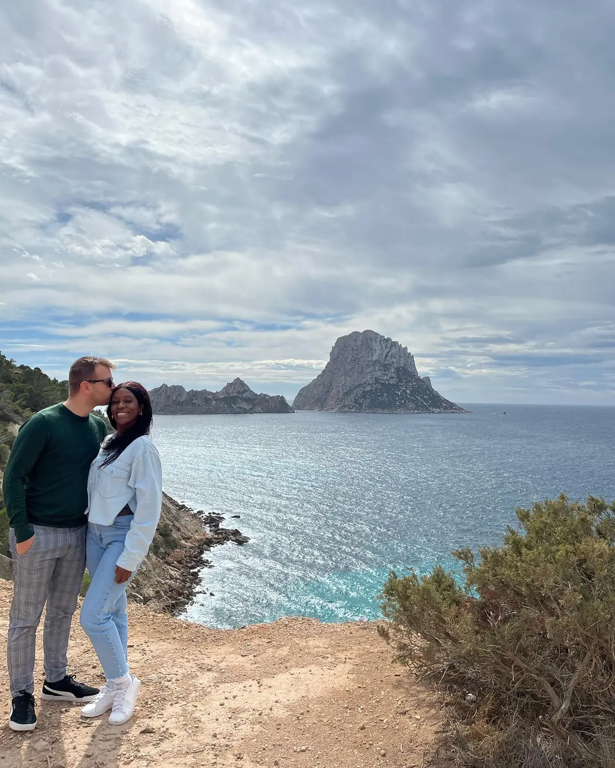 Us at a clifftop viewpoint with the mystical rock island of Es Vedrà rising from the sea behind, Ibiza
