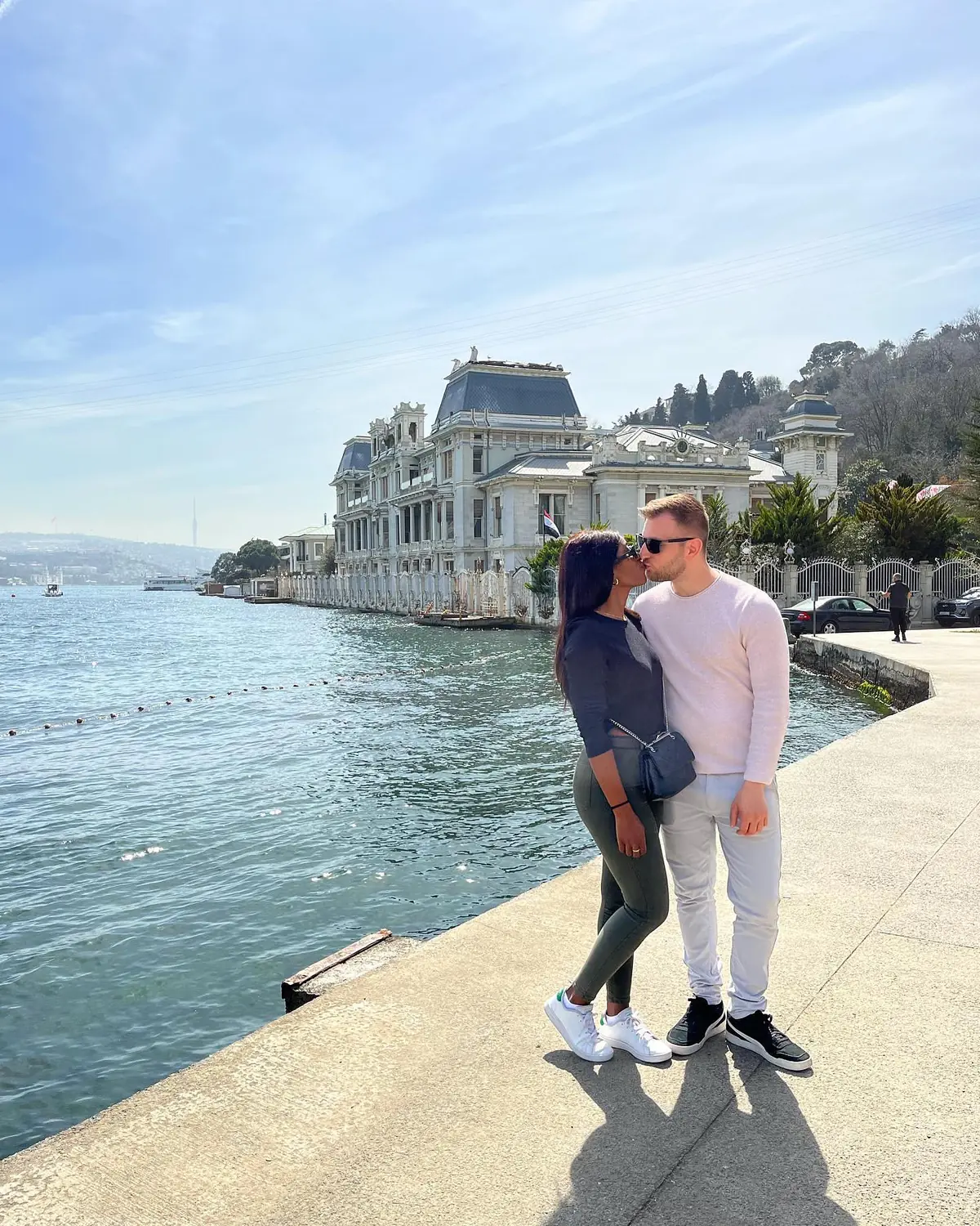 Us sharing a kiss on the Bosphorus promenade beside a grand waterfront mansion