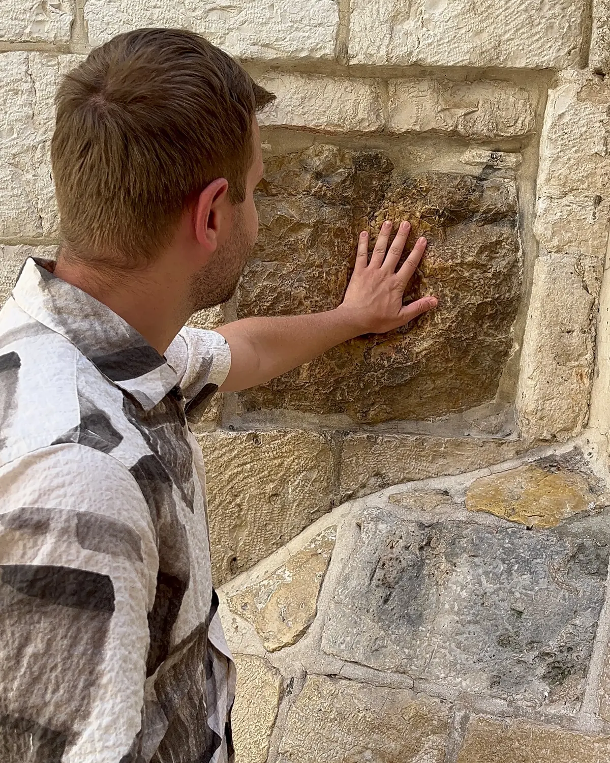 Andrew resting a hand on the worn stone of the Old City