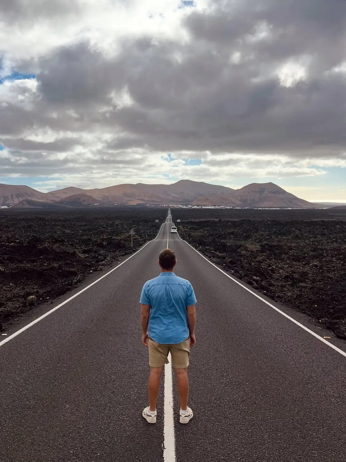 Andrew from behind on the same empty lava-field road stretching to the mountains