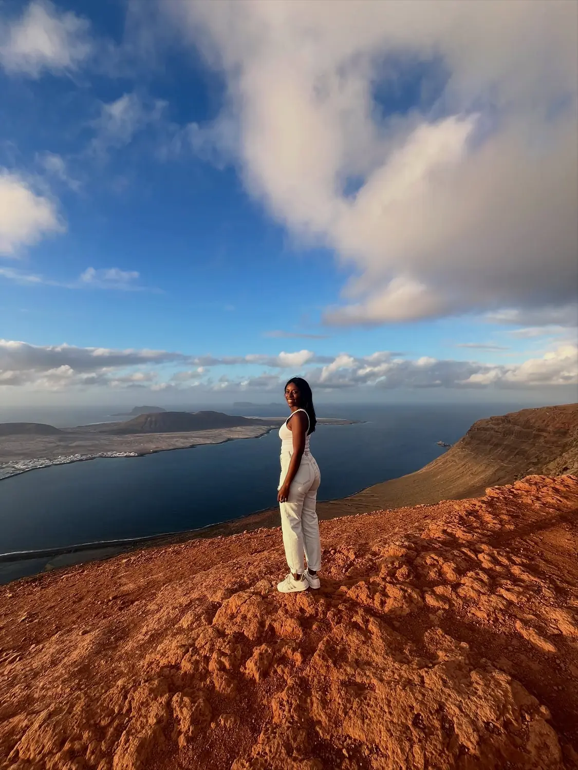 Melody on a red-earth clifftop at golden hour high above the island of La Graciosa and the sea