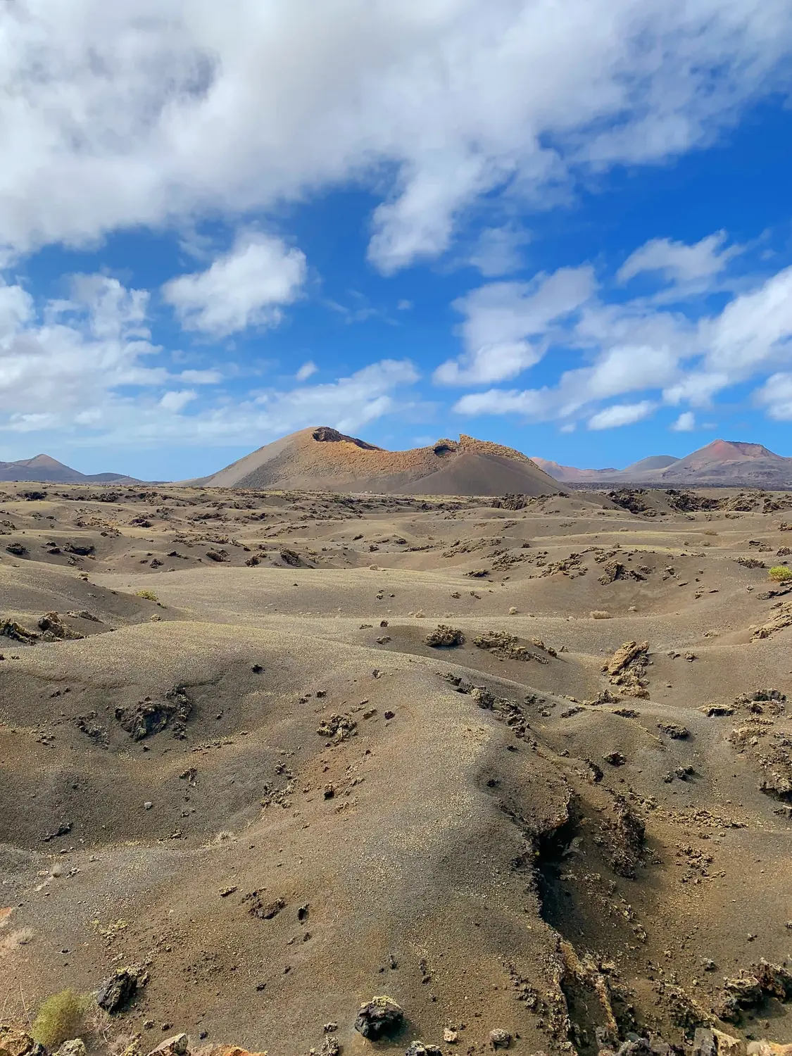 The Mars-like black-and-ochre volcanic plain and cones of Timanfaya National Park under a blue sky