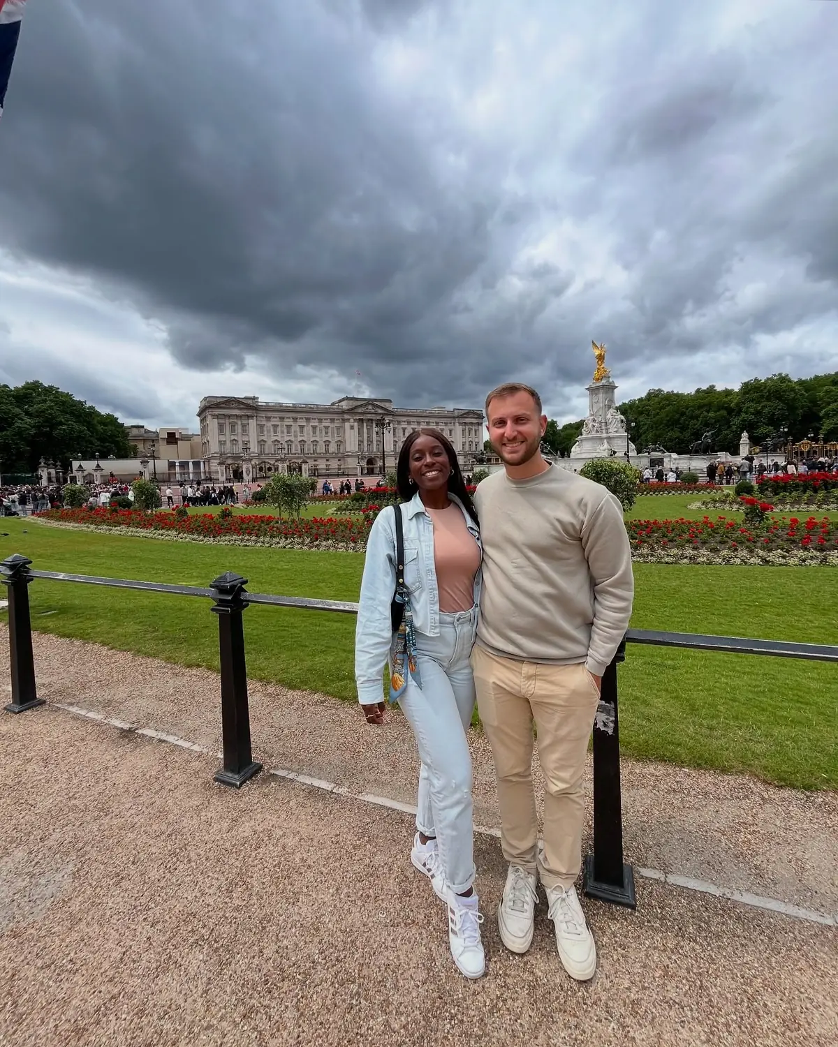 Us in front of Buckingham Palace and the golden Victoria Memorial under a dramatic sky