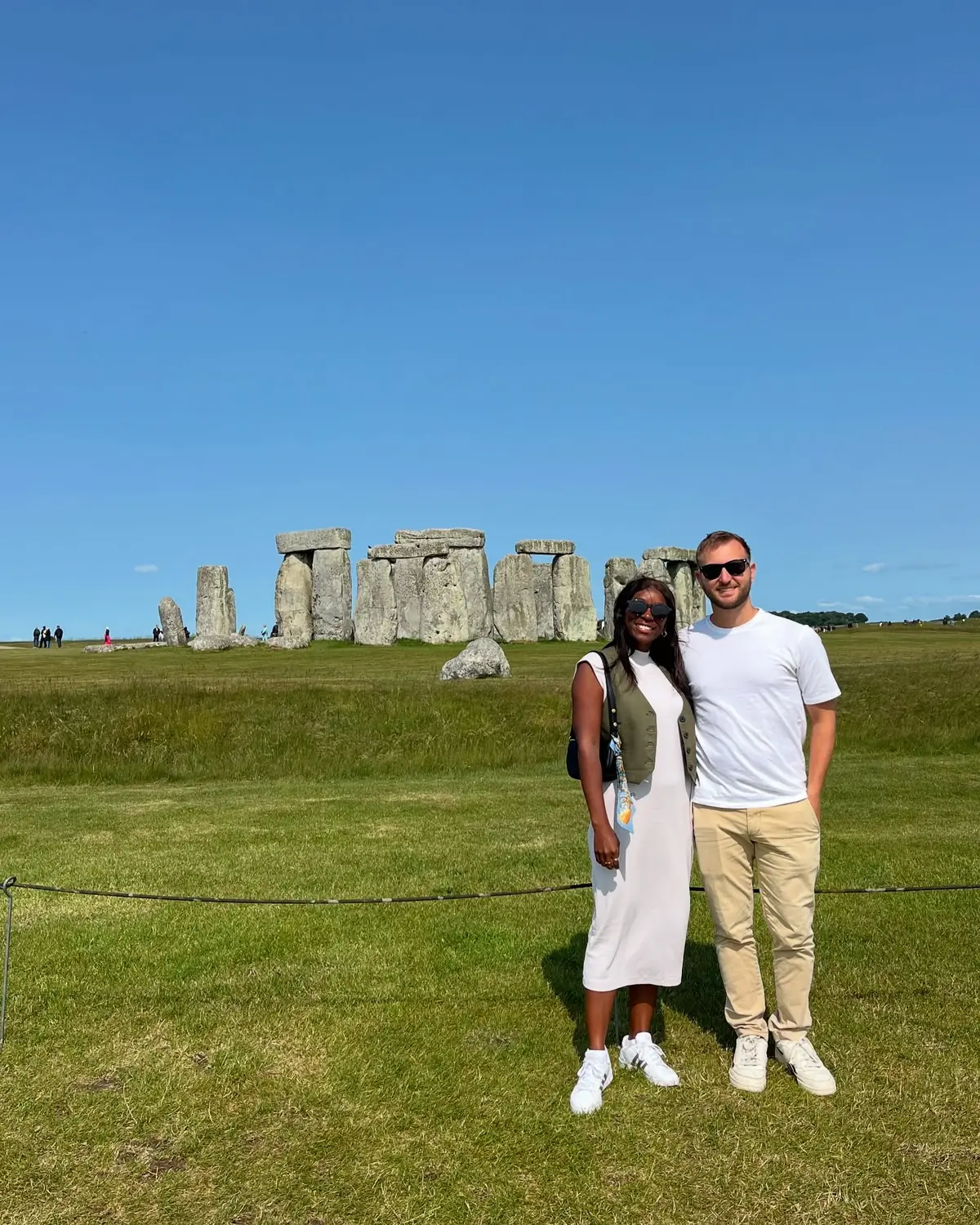 Us in front of the standing stones of Stonehenge under a clear blue sky