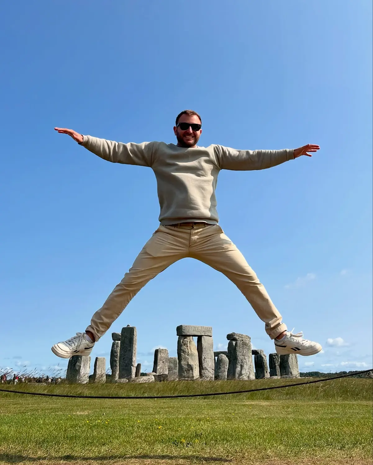Andrew mid-jump with arms and legs spread in front of Stonehenge