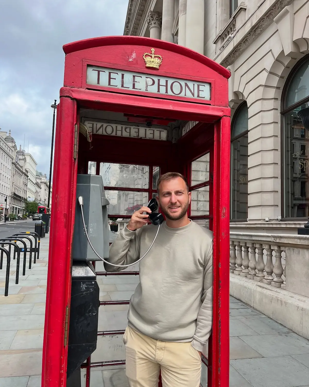 Andrew holding the receiver in a working red telephone box on Regent Street