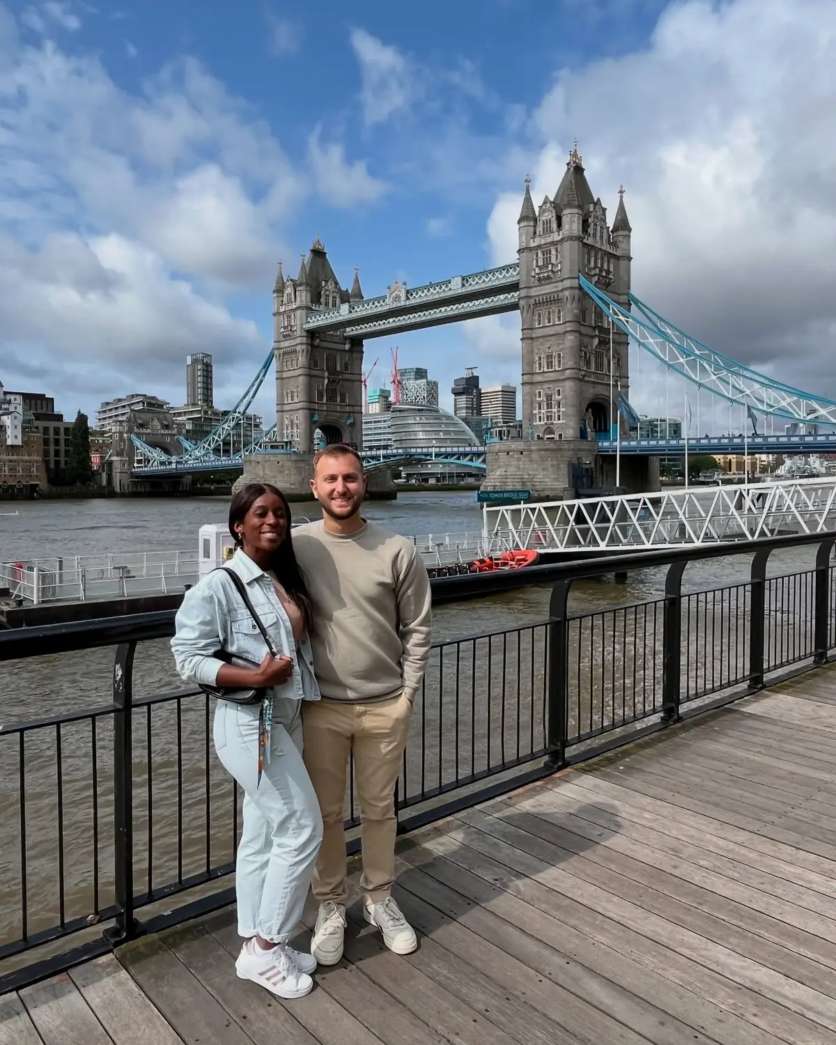 Us on the Thames riverside walk with Tower Bridge behind across the water